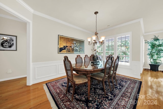 dining area with an inviting chandelier, light wood-style flooring, and ornamental molding