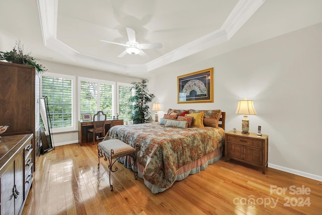 bedroom featuring a tray ceiling, ornamental molding, ceiling fan, and light wood-type flooring