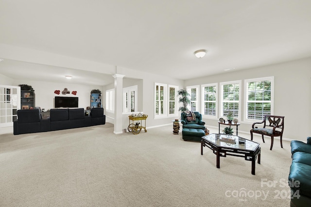 living room with carpet, decorative columns, and baseboards