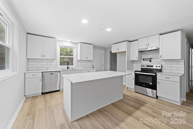 kitchen featuring a center island, stainless steel appliances, white cabinetry, and sink