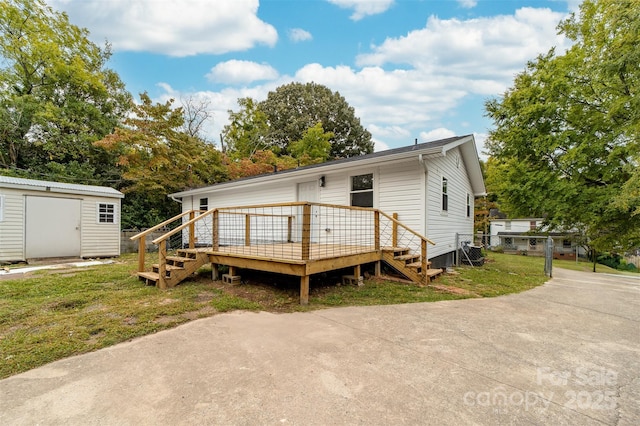 rear view of property featuring a shed and a deck