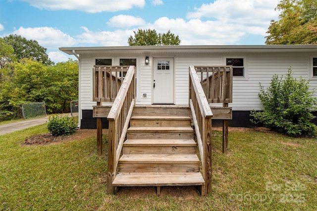 entrance to property featuring a yard and a deck