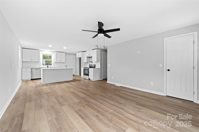 unfurnished living room featuring ceiling fan, sink, and light wood-type flooring