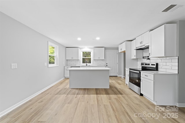 kitchen featuring white cabinetry, a center island, sink, light hardwood / wood-style floors, and stainless steel range with electric cooktop