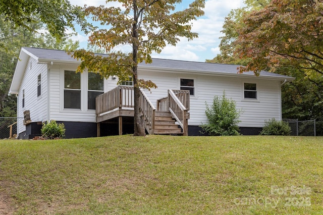 back of property featuring a deck and a lawn