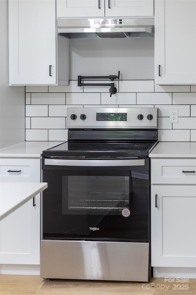 kitchen with white cabinets, decorative backsplash, and stainless steel range with electric cooktop