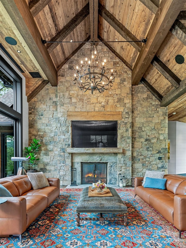 living room featuring beam ceiling, a stone fireplace, wooden ceiling, and an inviting chandelier