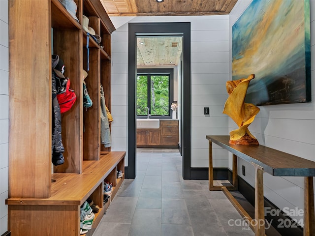 mudroom with wood ceiling, sink, and wood walls