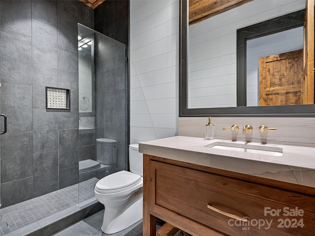 bathroom featuring tiled shower, vanity, toilet, and tile walls