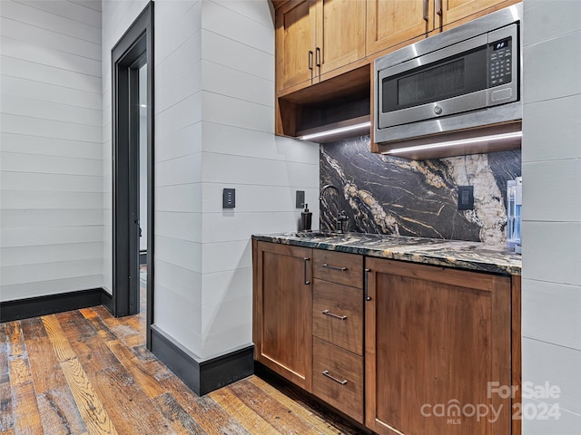 kitchen with tasteful backsplash, sink, dark stone countertops, and dark hardwood / wood-style floors