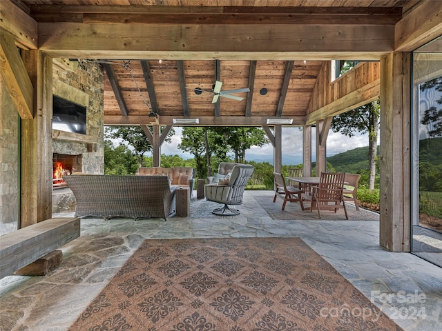 view of patio with a mountain view, an outdoor living space with a fireplace, and ceiling fan