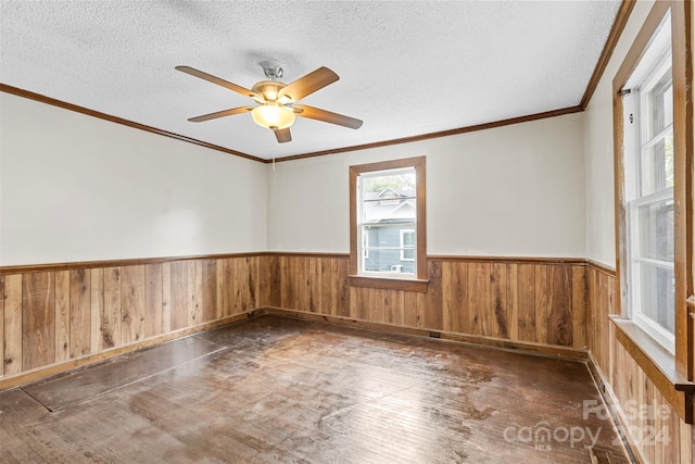 empty room with dark wood-type flooring, a textured ceiling, ornamental molding, and ceiling fan