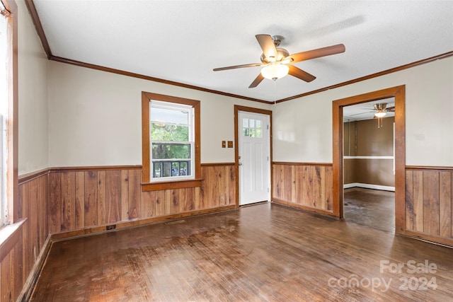 spare room with wooden walls, a textured ceiling, dark wood-type flooring, ceiling fan, and ornamental molding