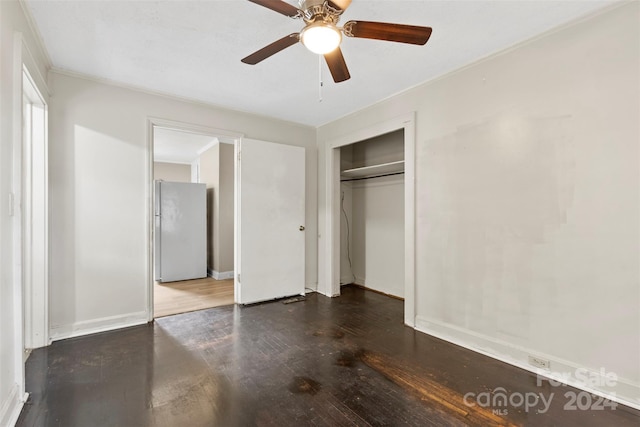 unfurnished bedroom with white fridge, a closet, hardwood / wood-style flooring, and ceiling fan