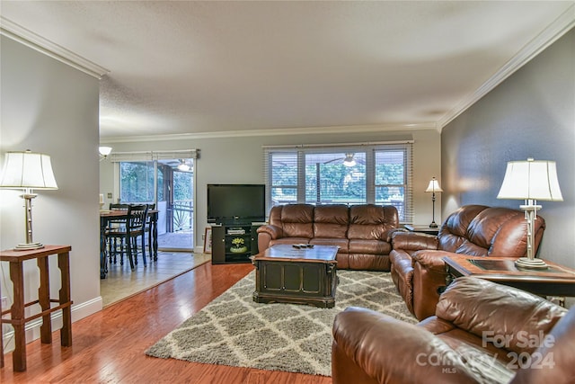 living room featuring hardwood / wood-style flooring, crown molding, and a healthy amount of sunlight