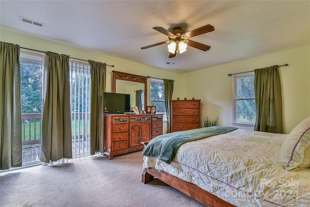 bedroom with ceiling fan, light colored carpet, access to exterior, and multiple windows