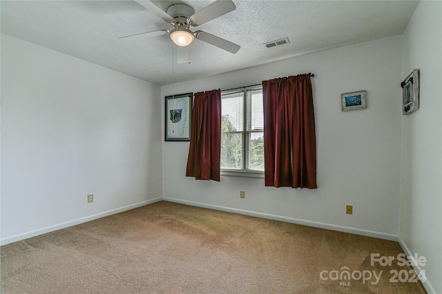 spare room featuring a textured ceiling, light colored carpet, and ceiling fan