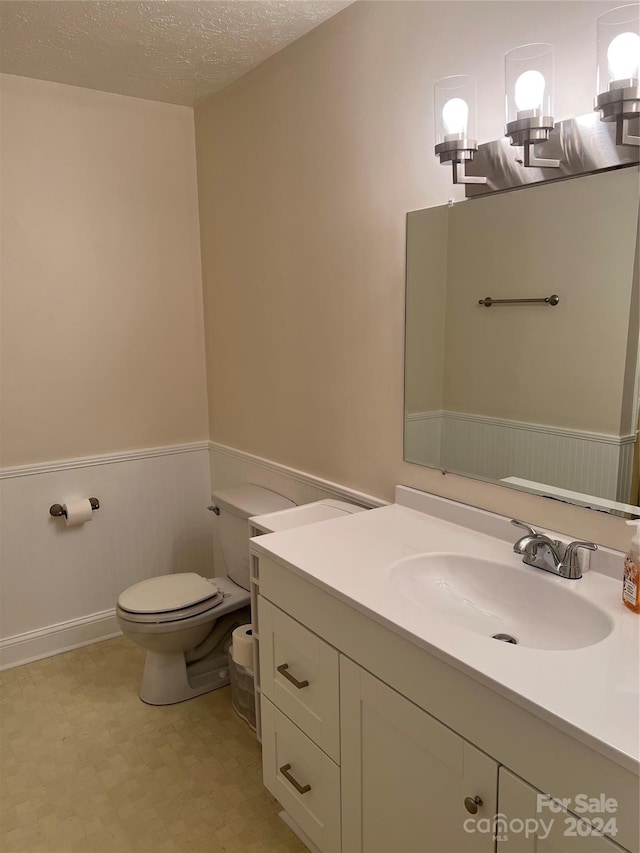 bathroom featuring vanity, toilet, and a textured ceiling