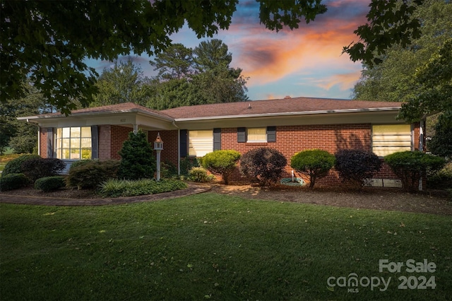 single story home with a lawn