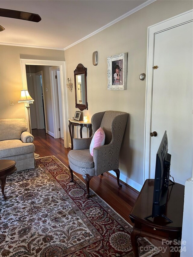 sitting room with dark wood-type flooring and crown molding