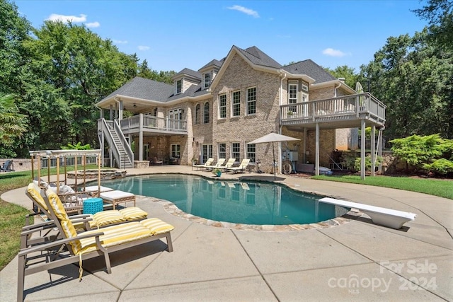 view of swimming pool featuring a patio area, a deck, and a diving board