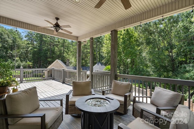 deck featuring ceiling fan and an outdoor living space with a fire pit