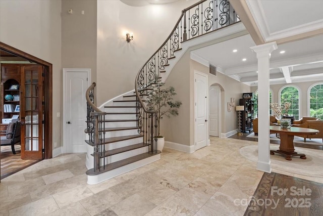 entryway with crown molding, beam ceiling, a towering ceiling, decorative columns, and coffered ceiling