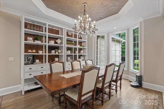 dining space with a raised ceiling, ornamental molding, and hardwood / wood-style flooring