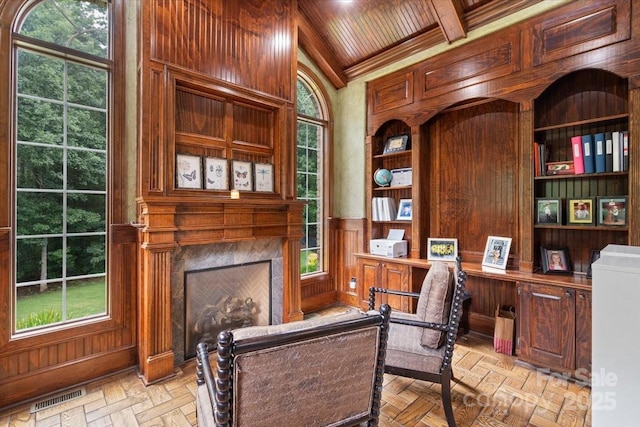 office area with beamed ceiling, light parquet flooring, wooden walls, and a high end fireplace