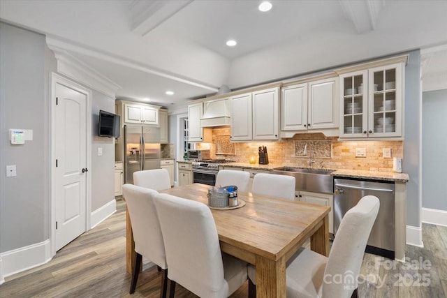 dining area featuring sink, beam ceiling, and light hardwood / wood-style flooring