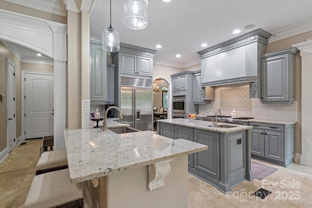 kitchen with stainless steel appliances, a kitchen island with sink, a breakfast bar area, and gray cabinetry