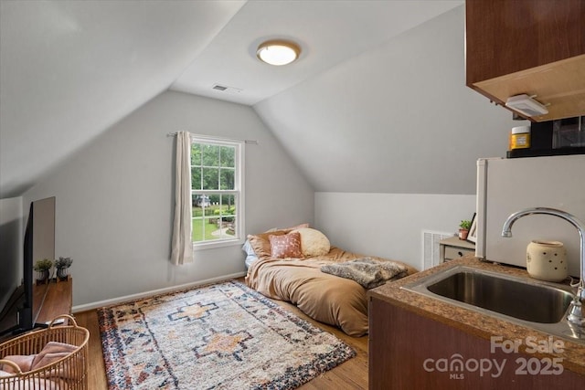 bedroom with lofted ceiling, wood-type flooring, and sink