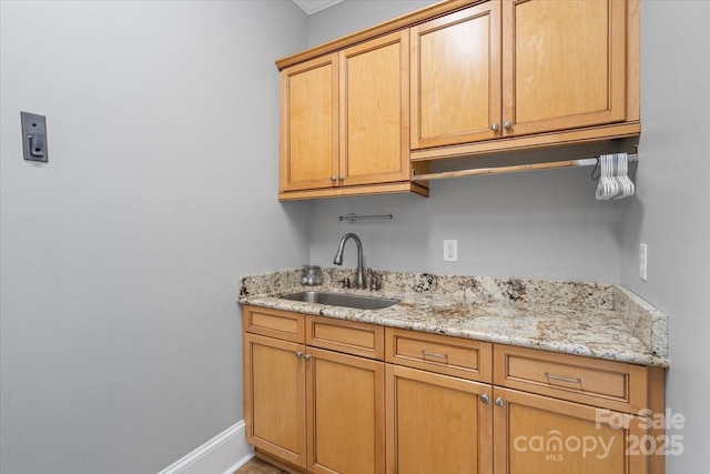 kitchen featuring light stone counters and sink