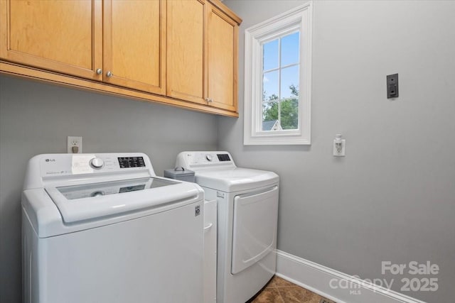 clothes washing area with cabinets and washer and dryer