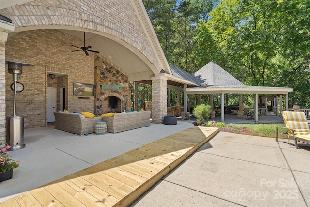 view of patio / terrace featuring ceiling fan and an outdoor living space with a fireplace