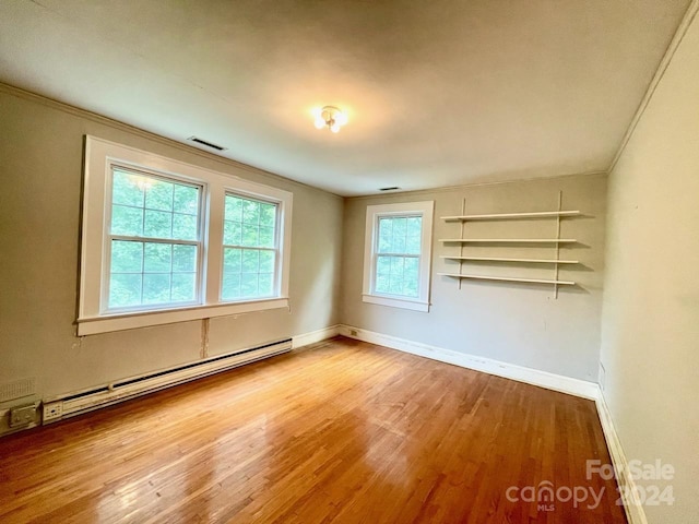 spare room with baseboard heating, light hardwood / wood-style flooring, and ornamental molding