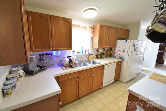 kitchen with a textured ceiling, crown molding, white appliances, and sink