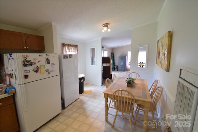 kitchen featuring white refrigerator, crown molding, lofted ceiling, and a textured ceiling