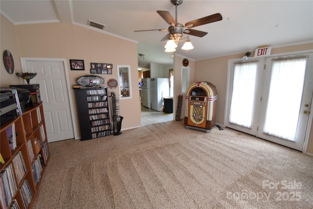 unfurnished living room featuring ceiling fan, light colored carpet, vaulted ceiling, and ornamental molding