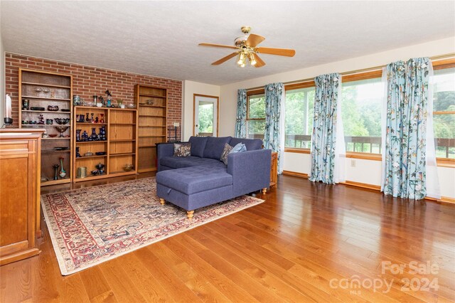 living room with a textured ceiling, brick wall, ceiling fan, and wood-type flooring