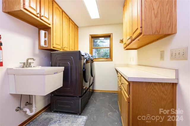 clothes washing area featuring washer / clothes dryer, cabinets, sink, and dark tile patterned flooring