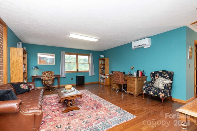 living room featuring a textured ceiling, brick wall, an AC wall unit, and hardwood / wood-style flooring