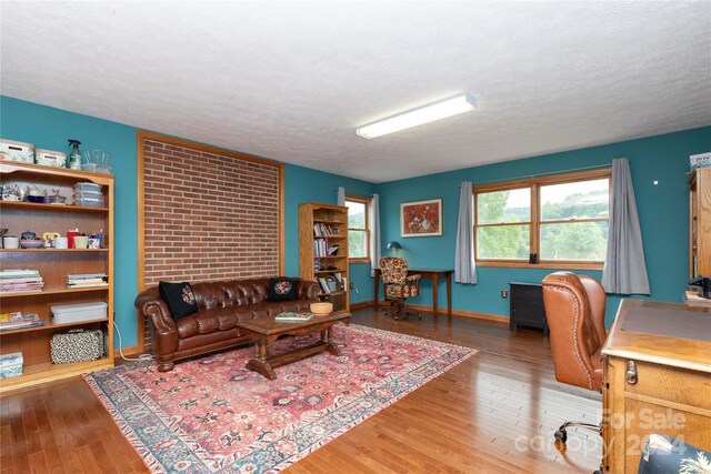 living room with brick wall, a textured ceiling, and hardwood / wood-style floors