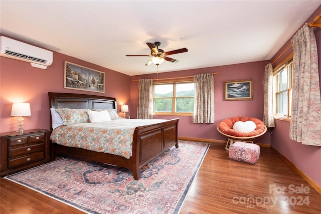 bedroom featuring ceiling fan, a wall unit AC, and hardwood / wood-style flooring