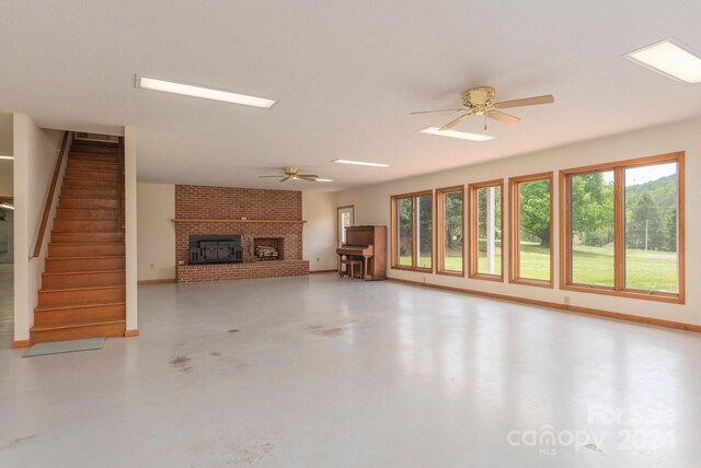 unfurnished living room featuring concrete flooring, ceiling fan, a fireplace, and brick wall