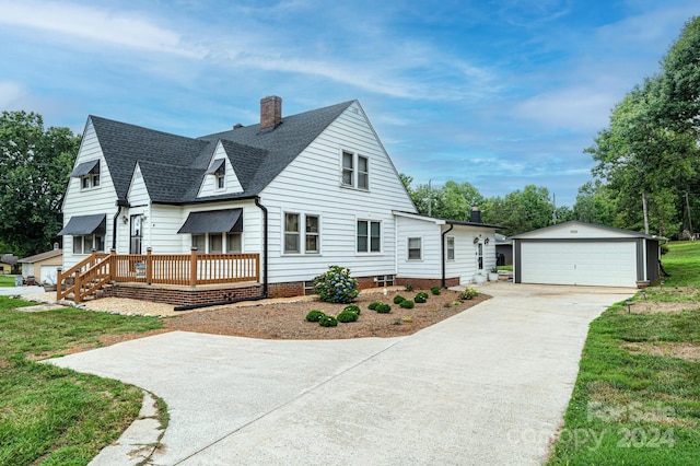 view of front of home with a garage, an outbuilding, a deck, and a front yard