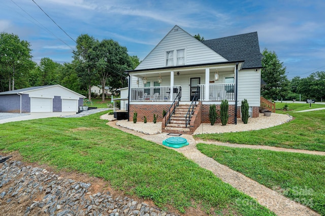 view of front of house with a garage, an outbuilding, a front yard, and covered porch