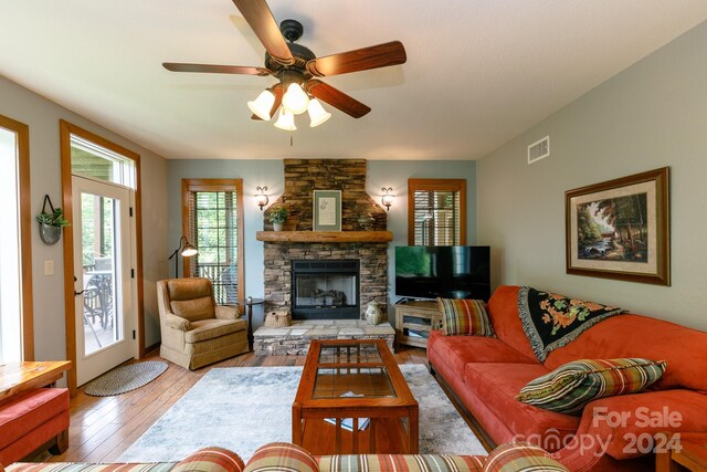 living room featuring a fireplace, light wood-type flooring, and ceiling fan