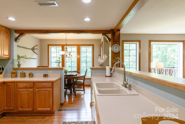 kitchen with visible vents, beam ceiling, light countertops, pendant lighting, and a sink