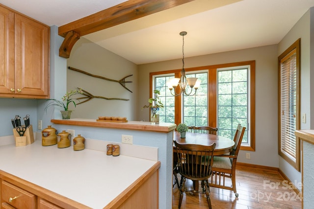 kitchen with a notable chandelier, a peninsula, light wood-style floors, light countertops, and hanging light fixtures